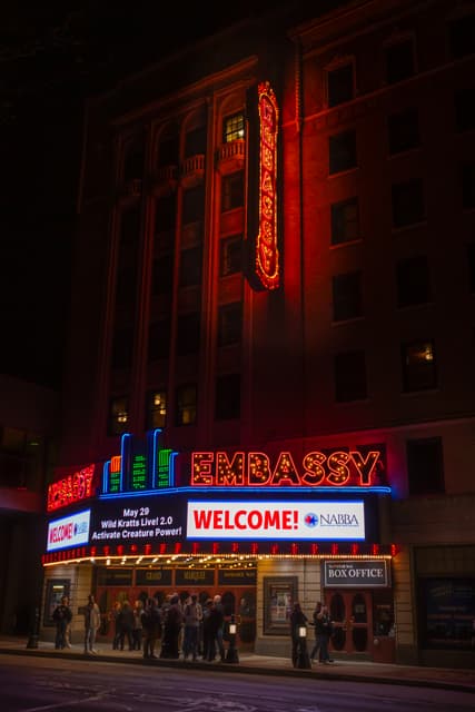 Embassy Theatre at night with neon sign and marquee welcoming NABBA