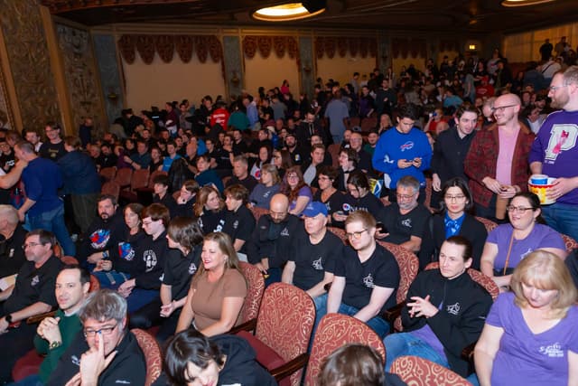 Crowded audience seated in an ornate historic theatre before a brass band contest session