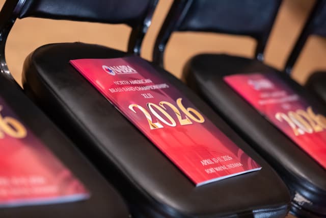 Red 2026 NABBA Championships programmes lying on black auditorium chairs