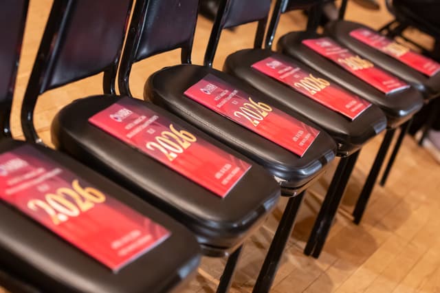 Red 2026 NABBA Championships programmes lying on a row of black chairs