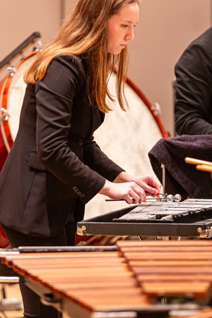 Percussionist playing a glockenspiel with a marimba and bass drum nearby