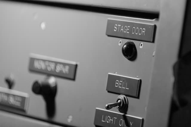 Black and white close-up of backstage panel with Stage Door, Bell and Light Only labels