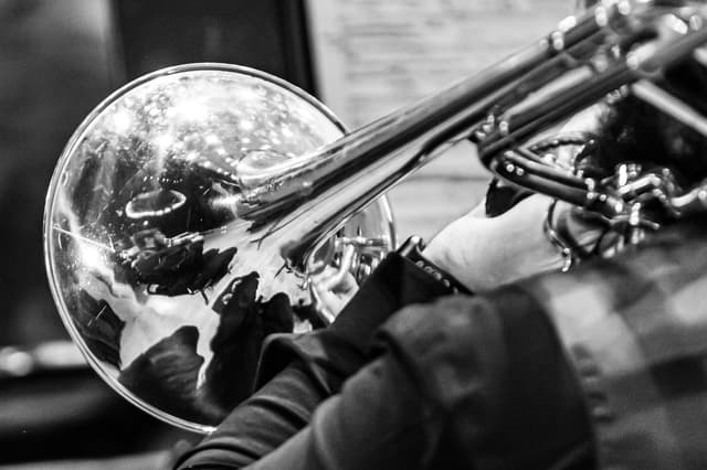 Black and white close-up of a trombone bell reflecting its surroundings