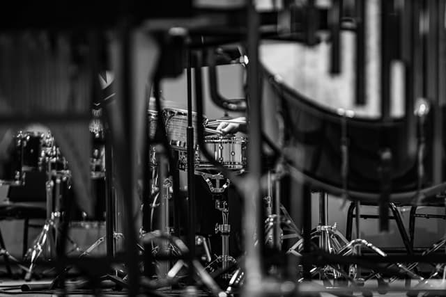Black and white view of a percussionist playing snare drum through stage stands