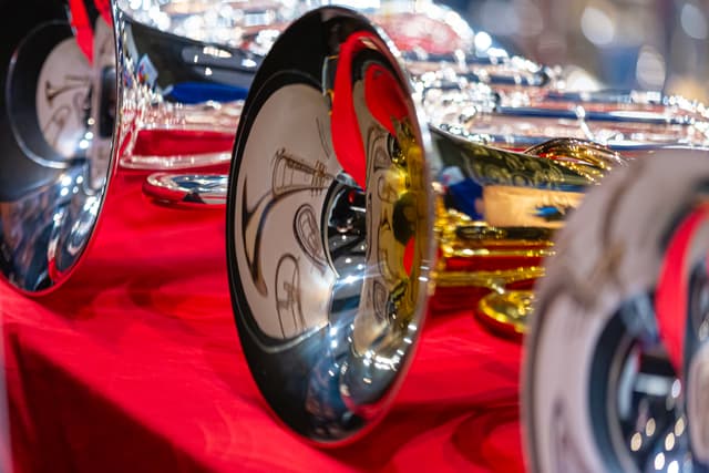 Shiny silver and gold brass instrument bells on a red cloth with reflections