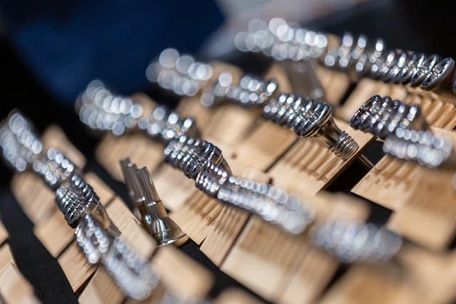 Rows of polished silver brass mouthpieces on wooden stands with sparkling blurred highlights