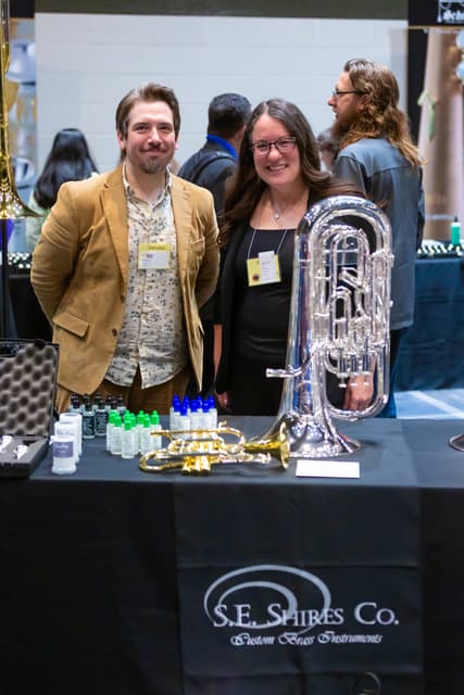 Two vendors at the S.E. Shires Co. stand with a silver euphonium and trumpet