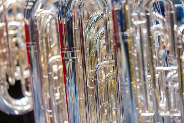 Close-up of several polished silver tubas with reflective tubing and valves