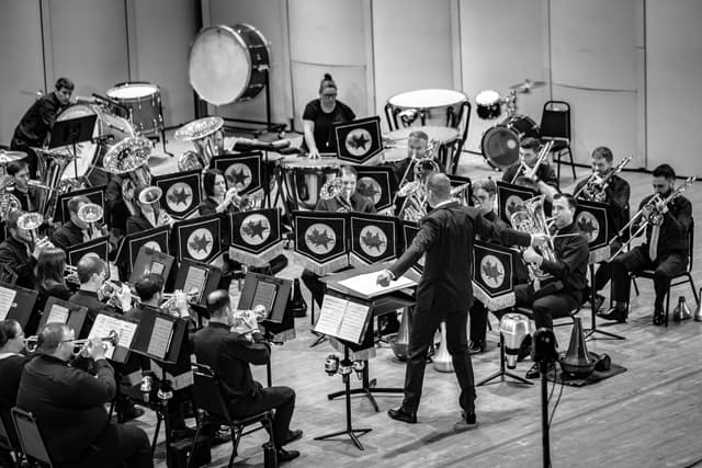 Conductor directing a brass band on stage with NABBA banners on stands