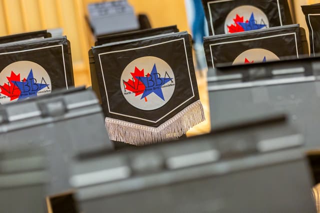 Close-up of NABBA logo banner on a black music stand with silver fringe