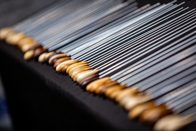 Rows of conducting batons with wooden handles and slender white shafts on black cloth